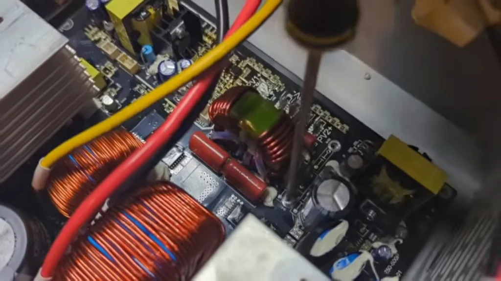 Close-up of a screwdriver adjusting mounting screws on the inverter circuit board.