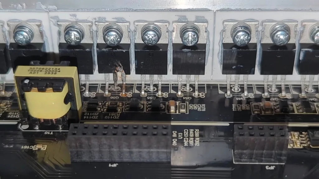 Close-up of a damaged power transistor mounted to an aluminum heatsink.