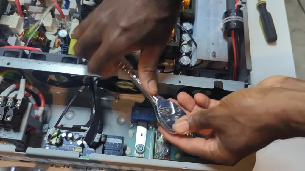 Using a ratchet wrench to tighten a heavy-duty bolt on the power terminal.
