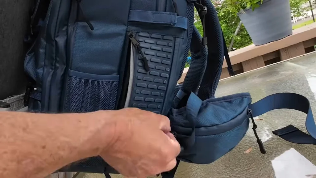 Hand opening the backpack pocket to reveal controls