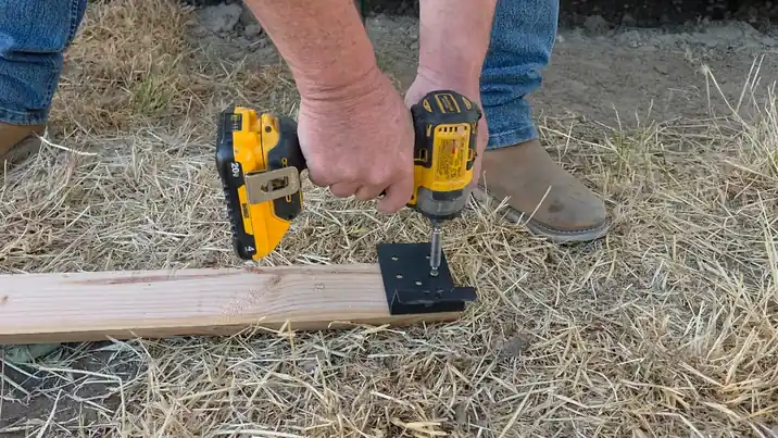 Close-up of black T-post brackets being test-fitted onto a steel post.
