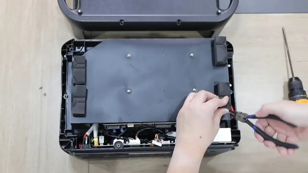 Technician using pliers to disconnect internal power wiring