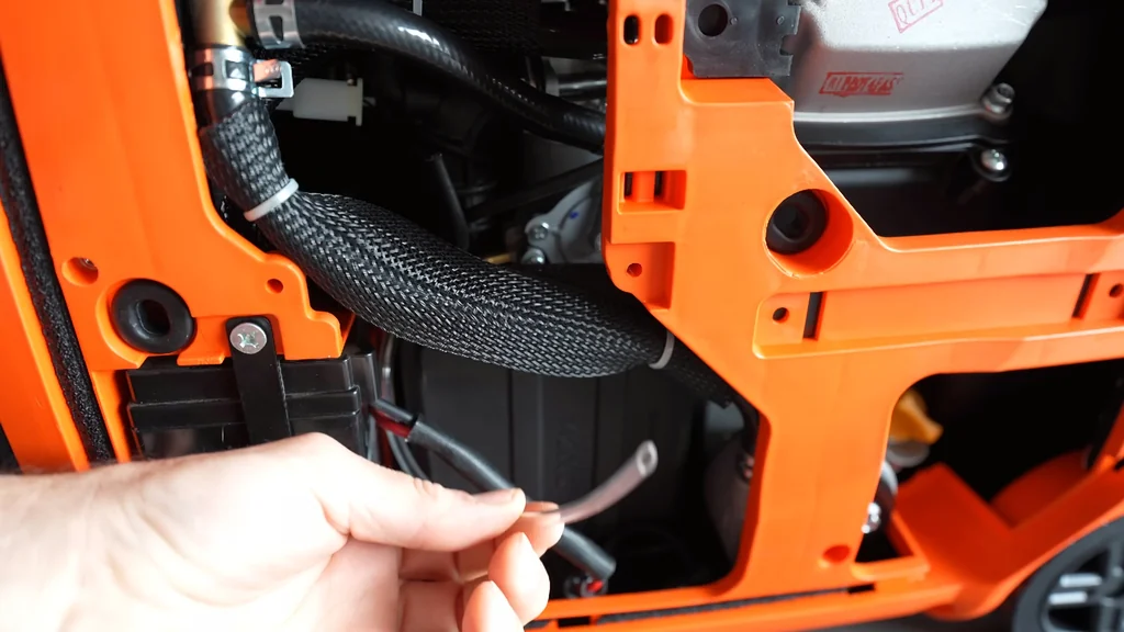 Hand pointing to generator carburetor drain tube