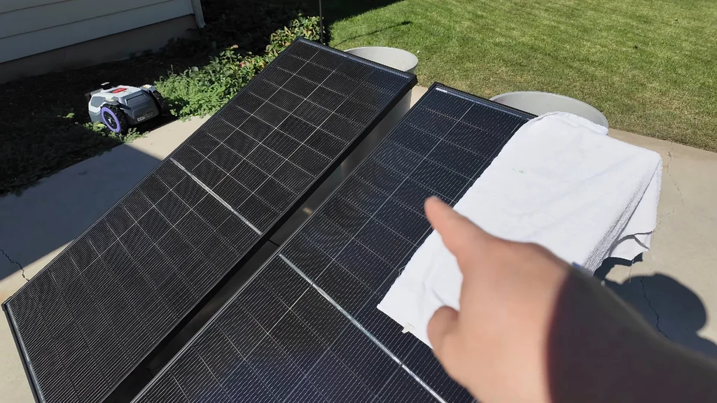 Hand pointing at a partially covered solar panel