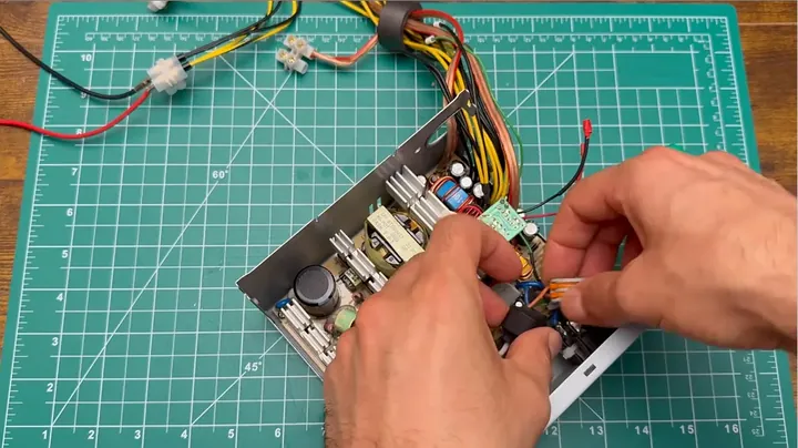 Close-up of internal circuit board with stripped wires, demonstrating the green PS_ON lead strapped to ground