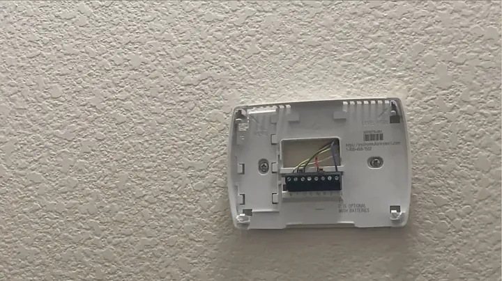 Close-up view of exposed low voltage thermostat subbase terminals before wire removal