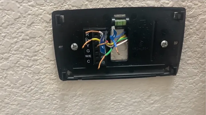 Screwdriver tightening mounting screws into wall anchors through the leveled subbase