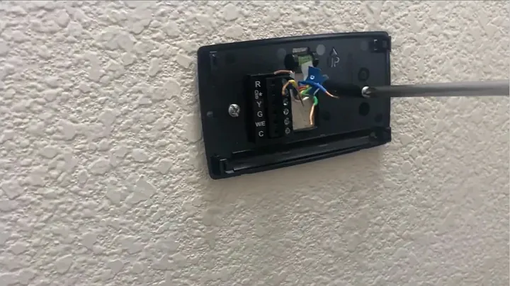 Hands trimming low-voltage copper thermostat wire ends to uniform length using wire strippers