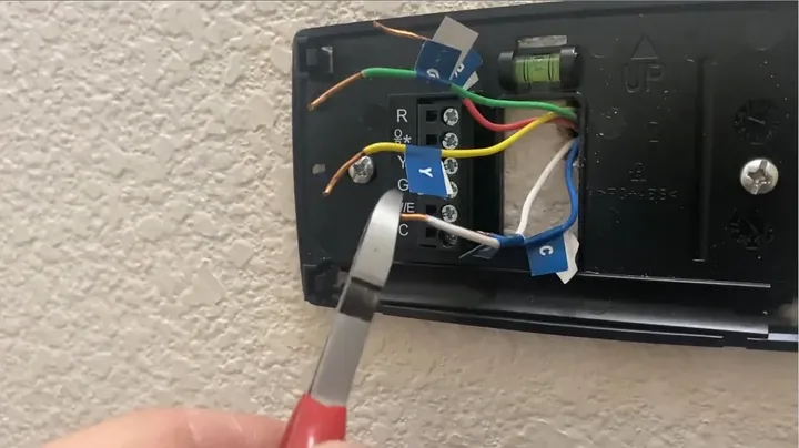 Pliers performing a gentle pull test on seated thermostat wires in the terminal block