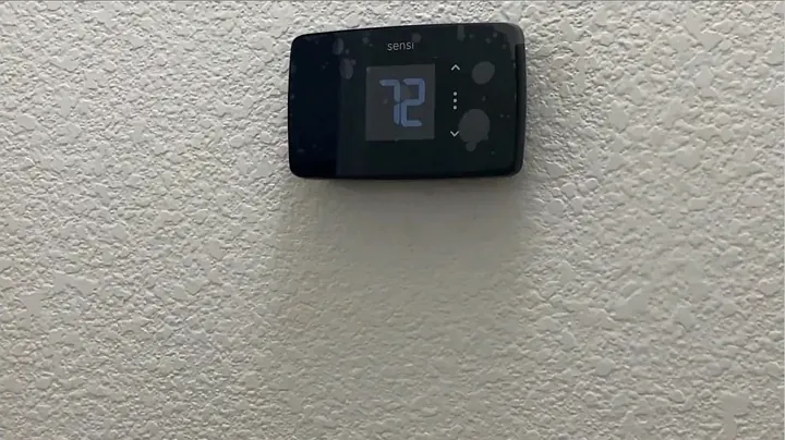 Smart thermostat display mounted on the wall plate with screen powering on