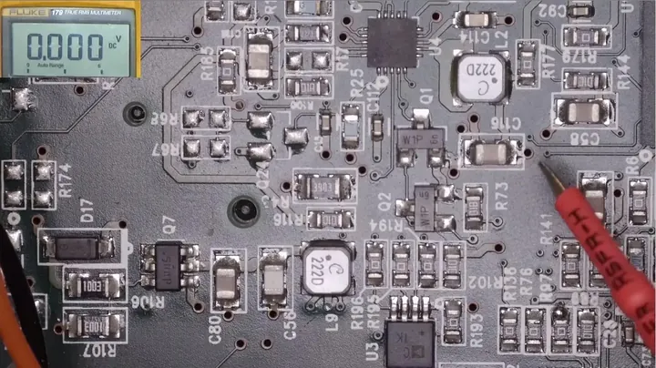 Digital multimeter probing capacitor leads on the circuit board
